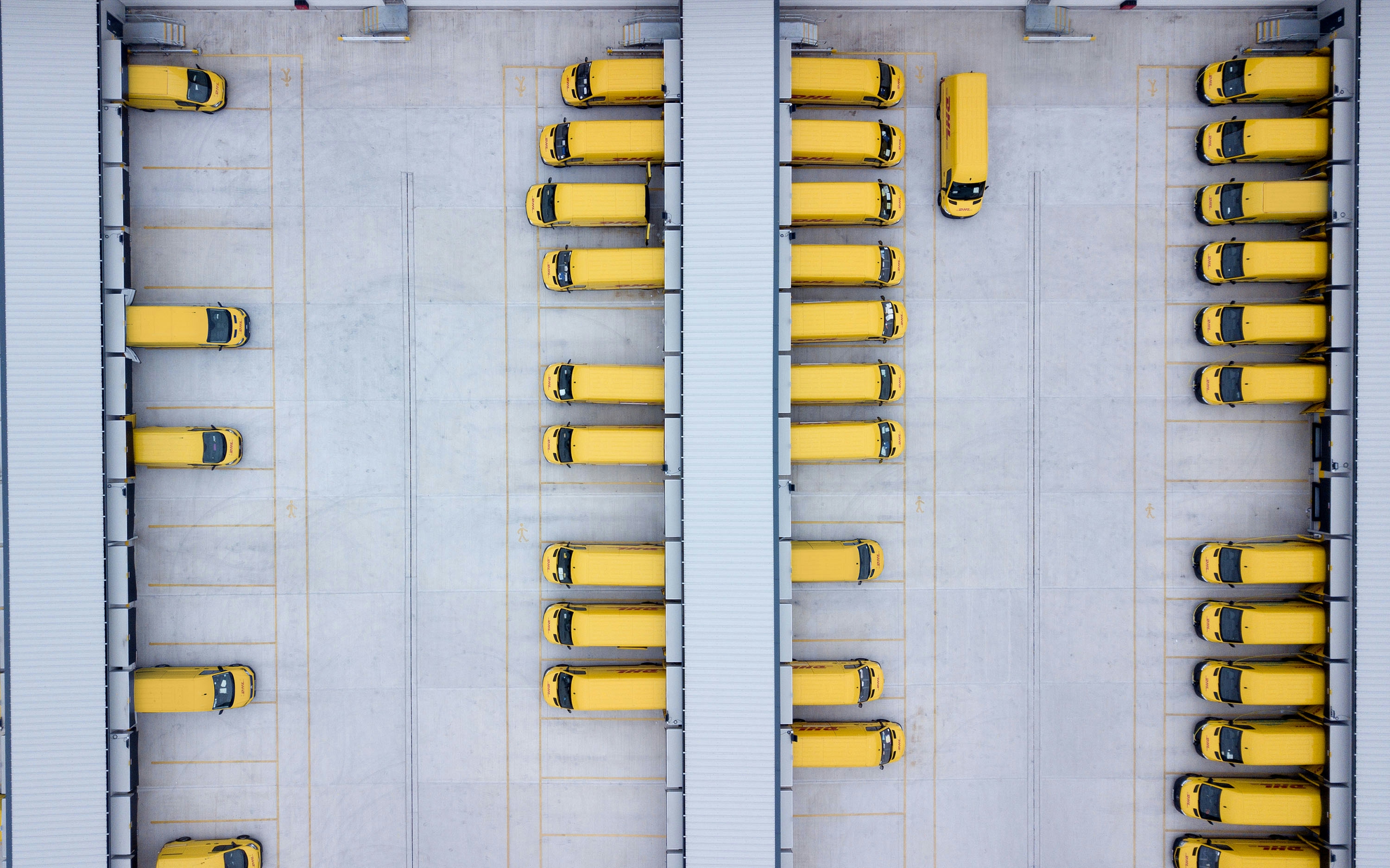 Yellow electric vans parked at a depot.